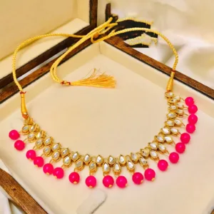 A stunning Kundan choker necklace in a beautiful shade of pink, adorned with intricate gold detailing and delicate pink gemstones. This elegant piece exudes grace and sophistication, perfect for adding a touch of glamour to any outfit.