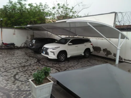 Modern car parking shed design in Pakistan, showcasing innovative architecture with a top membrane crafted from durable tensile fabric. The structure provides Sun and Rain protection for vehicles.