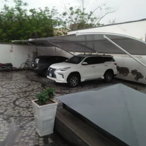 Modern car parking shed design in Pakistan, showcasing innovative architecture with a top membrane crafted from durable tensile fabric. The structure provides Sun and Rain protection for vehicles.