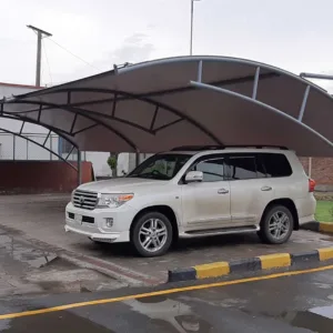 an innovative car parking shade design at the best price in Pakistan is now available. This modern car parking shed features a tensile fabric membrane for perfect vehicle protection from sun and rain. Tensile fabric structures are more reliable and long-lasting. This car parking shed was installed at Sadaqat Textile, Faisalabad